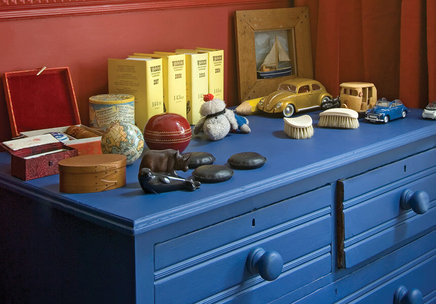 Estate Eggshell im Farbton Drawing Room Blue auf einer Kommode vor einer roten mit Modern Eggshell gestrichenen Wand